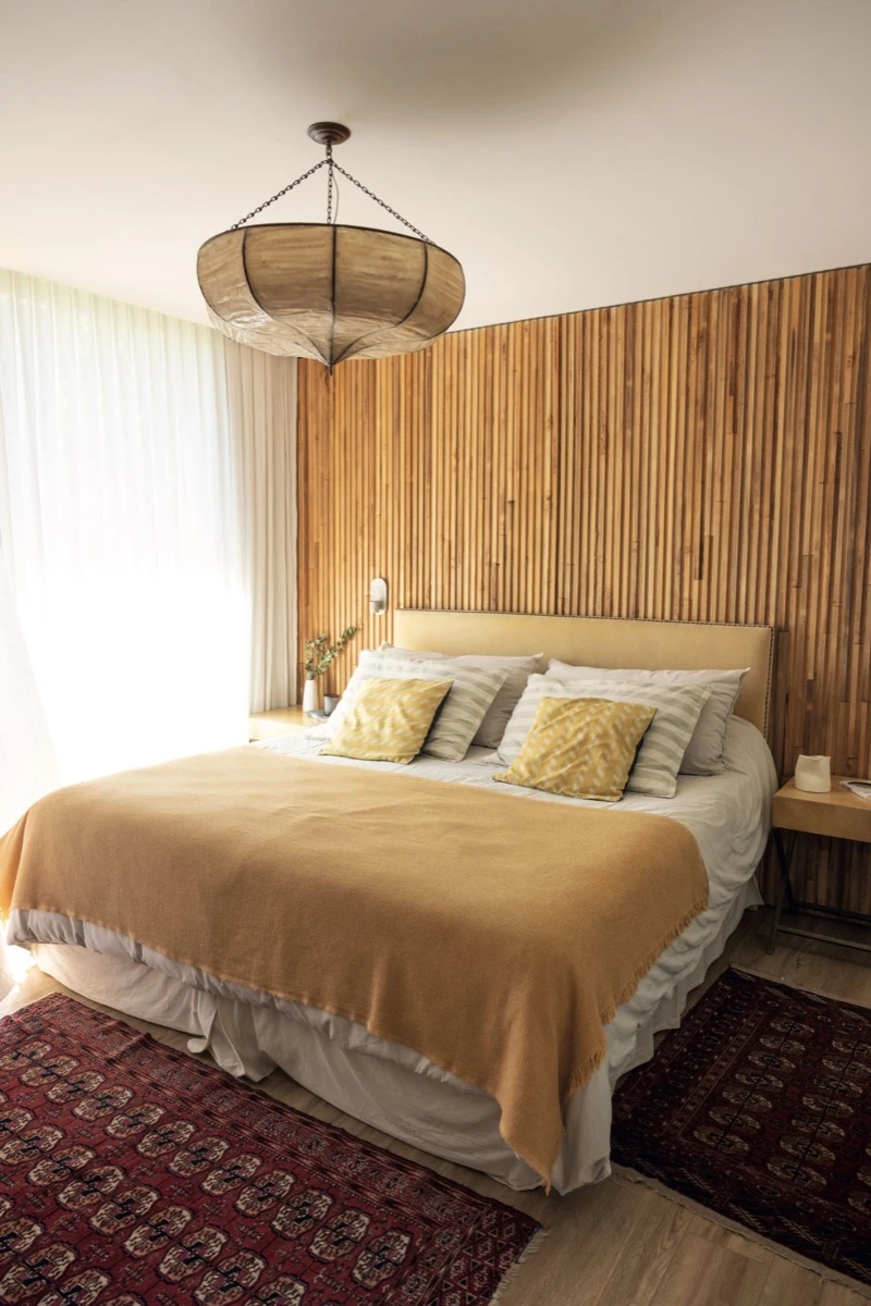 En el dormitorio principal el gran revestimiento de pared con listones de madera aporta textura y calidez. 