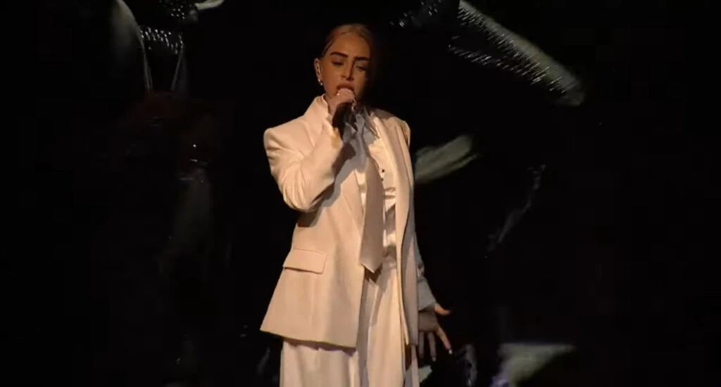 Nicki Nicole eligió un rodete pulido con un mechón suelto, potenciando el contraste entre el rubio y el morocho de su cabello.