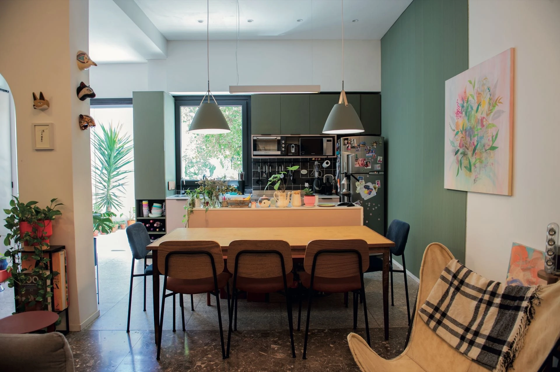 Y el nexo entre ambos mundos es una isla rosada, que sirve como mesada para cocinar y, a su vez, funciona como respaldo del banco que acompaña la mesa en madera natural del comedor. 