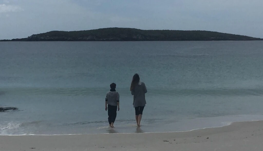 María con uno de sus hijos en la orilla del mar.