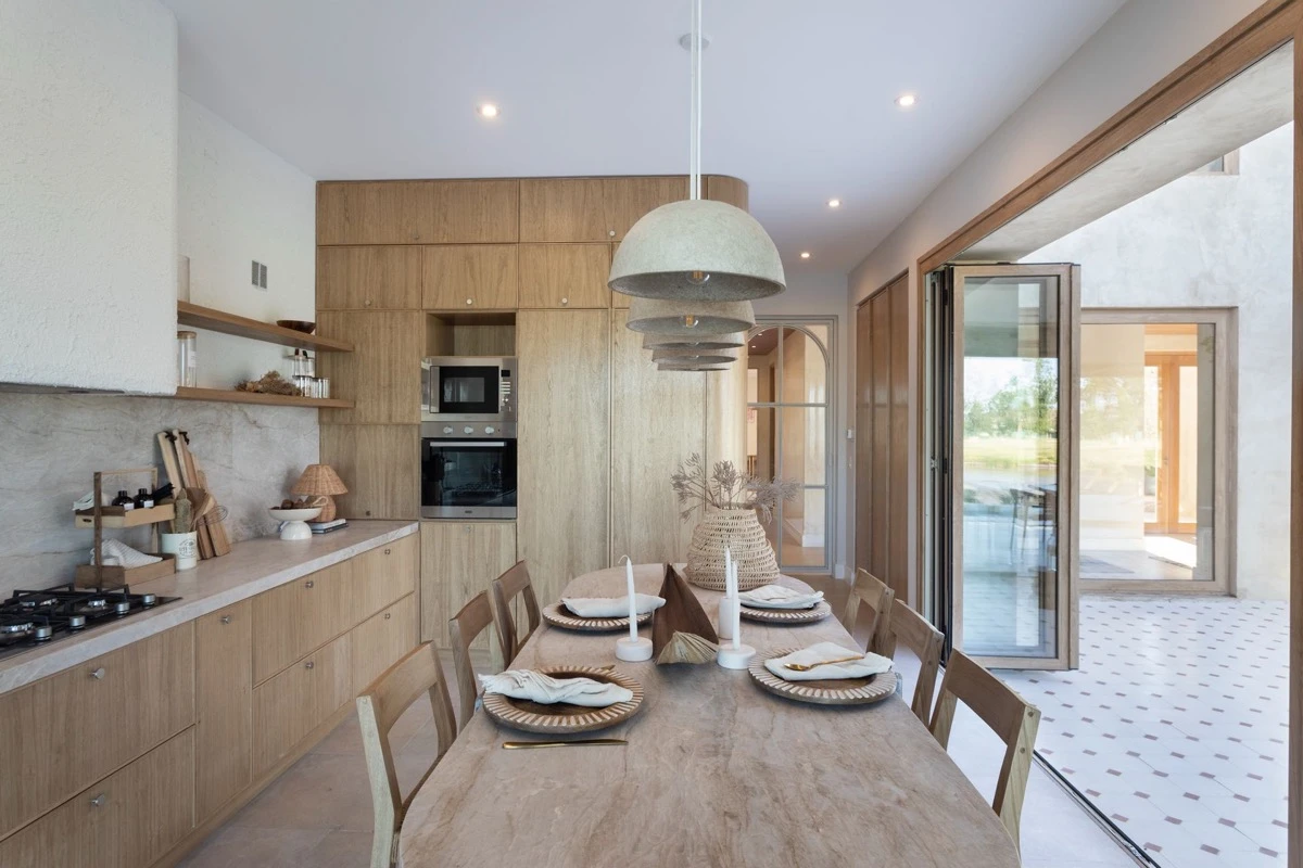 La cocina replica la lógica de apertura con un ventanal plegable. 