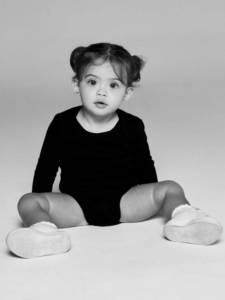 En otra postal, la niña aparece sentada en el piso mirando a cámara con curiosidad.