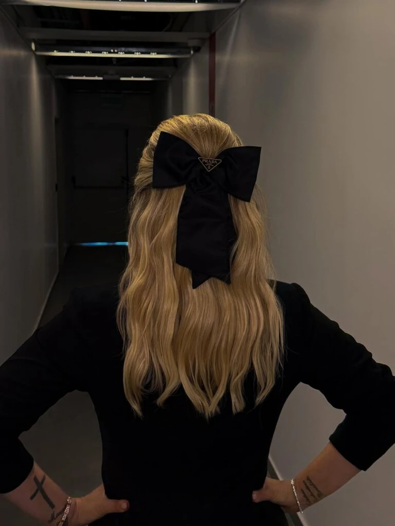 El elemento más destacado apareció en el peinado. Un lazo negro firmado por Prada se convirtió en el detalle inesperado que rompió con la sobriedad del look y sumó un aire romántico y actual.