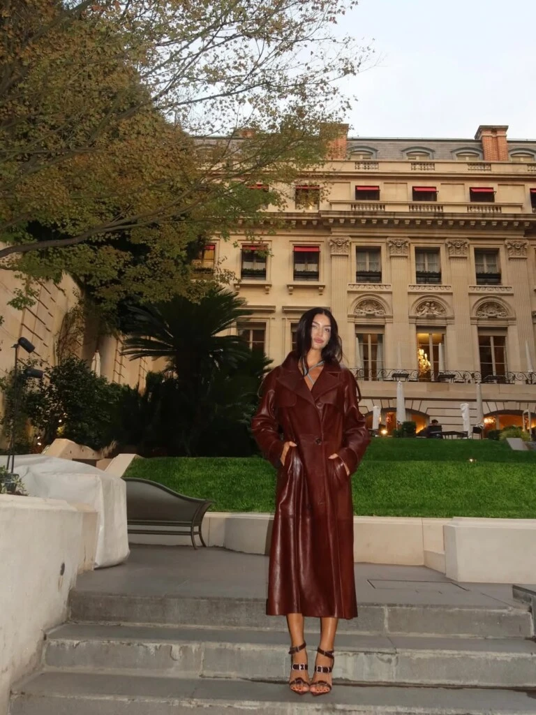 El diseño presenta una silueta clásica, con solapas amplias y corte recto, que estiliza la figura de la modelo de manera natural. 