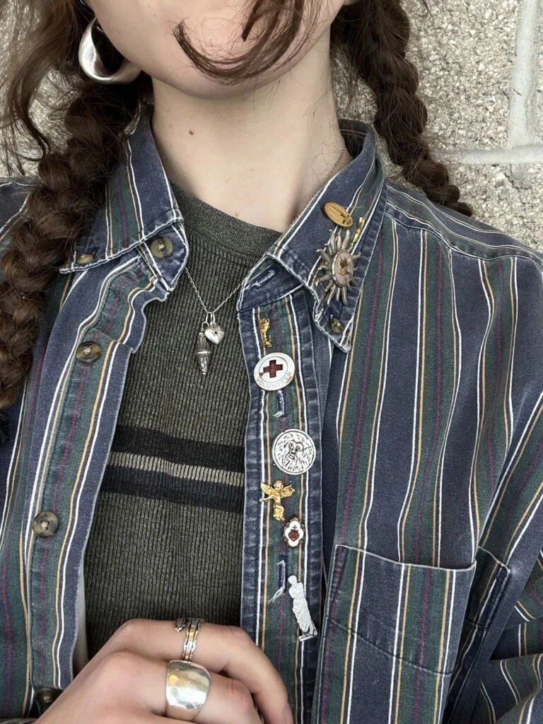 Los prendedores funcionan como una herramienta de intervención inmediata. No alteran la estructura de la prenda, pero sí transforman por completo su lectura visual.