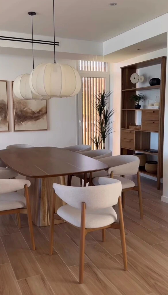 Una mesa de madera se convierte en el eje del ambiente, rodeada de sillas tapizadas en tonos claros que aportan sofisticación sin resignar comodidad.
