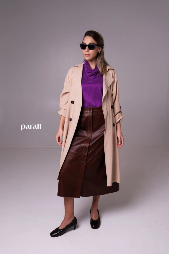 Trench de gabardina liviana color beige @concepcion.b.a; top musculosa de cupro y viscosa, con cuello alto @claraibargurenoficial; falda de cuero marrón con botones delanteros @mv.leather.studio; zapatos marrones taco fino, bajo @mishkabuenosaires; aros dorados @tina.allo; anteojos cat eyes marco negro @absurda_optica