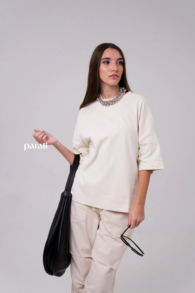 Remerón oversize Manteca @laspepasinst; pantalón de gabardina ancho con bolsillos delanteros @pruneoficial; zapatos bajos de cuero @oggizapatos; bolso de cuero negro @johnhicksba; anteojos de sol marco negro @bplusd.ar; collar de perlas @gingerjoyeria; collar de esferas plateadas @pruneoficial.