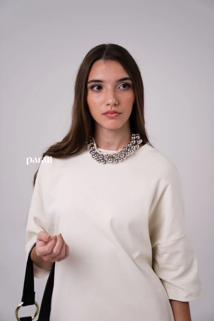 Remerón oversize Manteca @laspepasinst; pantalón de gabardina ancho con bolsillos delanteros @pruneoficial; zapatos bajos de cuero @oggizapatos; bolso de cuero negro @johnhicksba; anteojos de sol marco negro @bplusd.ar; collar de perlas @gingerjoyeria; collar de esferas plateadas @pruneoficial.