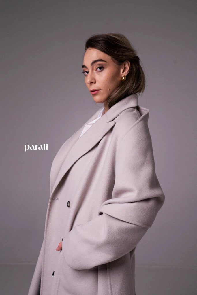 Tapado de paño cruzado color visón @mishkabuenosaires; camisa blanca de poplín, botón con brillos @concepcion.b.a; pantalón sastrero azul corte recto @laspepasinst; zapatos bajos de charol rojo y sobre de cuero negro @pruneoficial; aros dorados @tina.allo; anteojos de marco blanco @absurda_optica