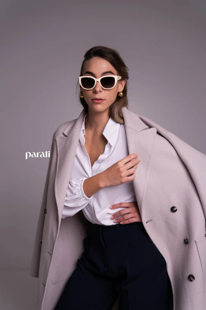 Tapado de paño cruzado color visón @mishkabuenosaires; camisa blanca de poplín, botón con brillos @concepcion.b.a; pantalón sastrero azul corte recto @laspepasinst; zapatos bajos de charol rojo y sobre de cuero negro @pruneoficial; aros dorados @tina.allo; anteojos de marco blanco @absurda_optica