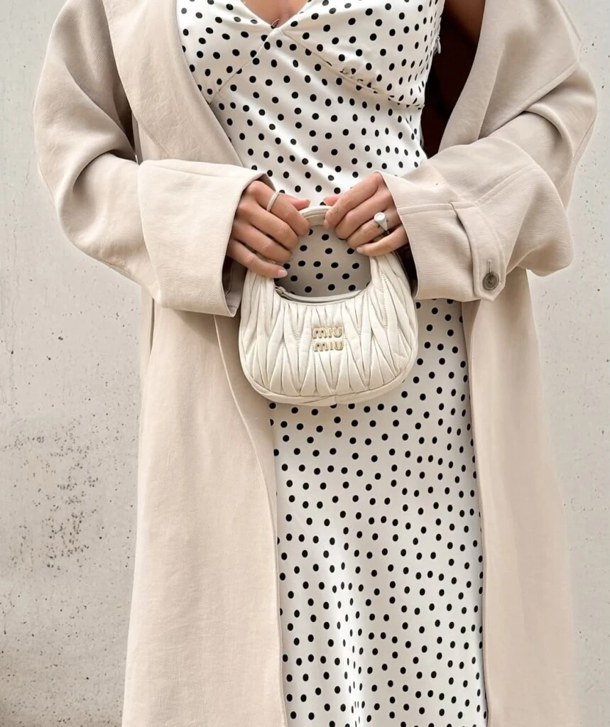 Como complemento, incorporó un mini bag fruncido de Miu Miu en tono crema, anillos plateados y gafas negras, logrando un equilibrio entre minimalismo y sofisticación.