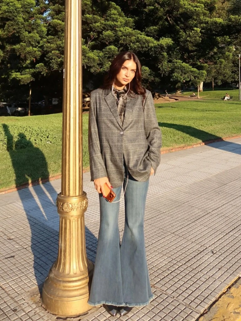 El outfit se completa con botas negras en punta, que estilizan la figura y suman un toque retro que dialoga con el resto de las prendas.