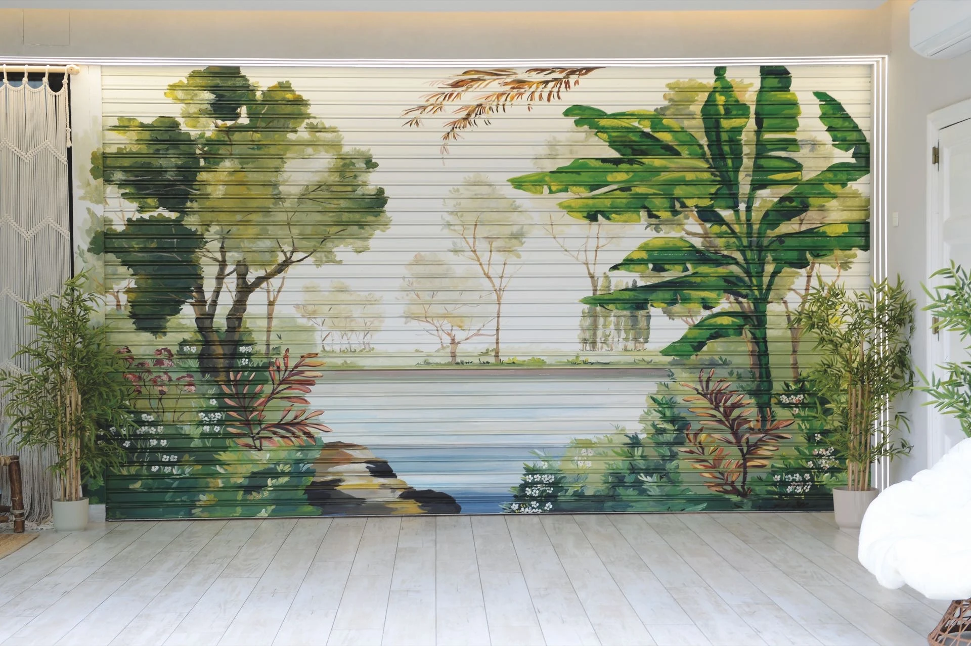La persiana metálica separa la cocina de la galería con un paisaje tropical.