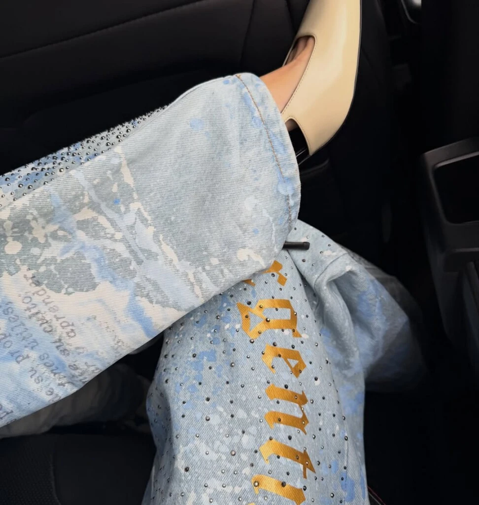 De silueta amplia y cómoda, el diseño se destacó por su lavado claro con efecto desgastado y detalles batik, además de aplicaciones de strass distribuidas en toda la prenda.