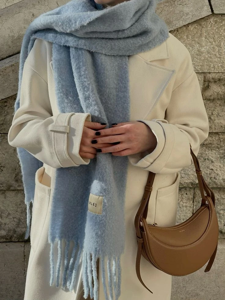 Un trench coat blanco o marfil combinado con una bufanda celeste crea un look elegante y atemporal.