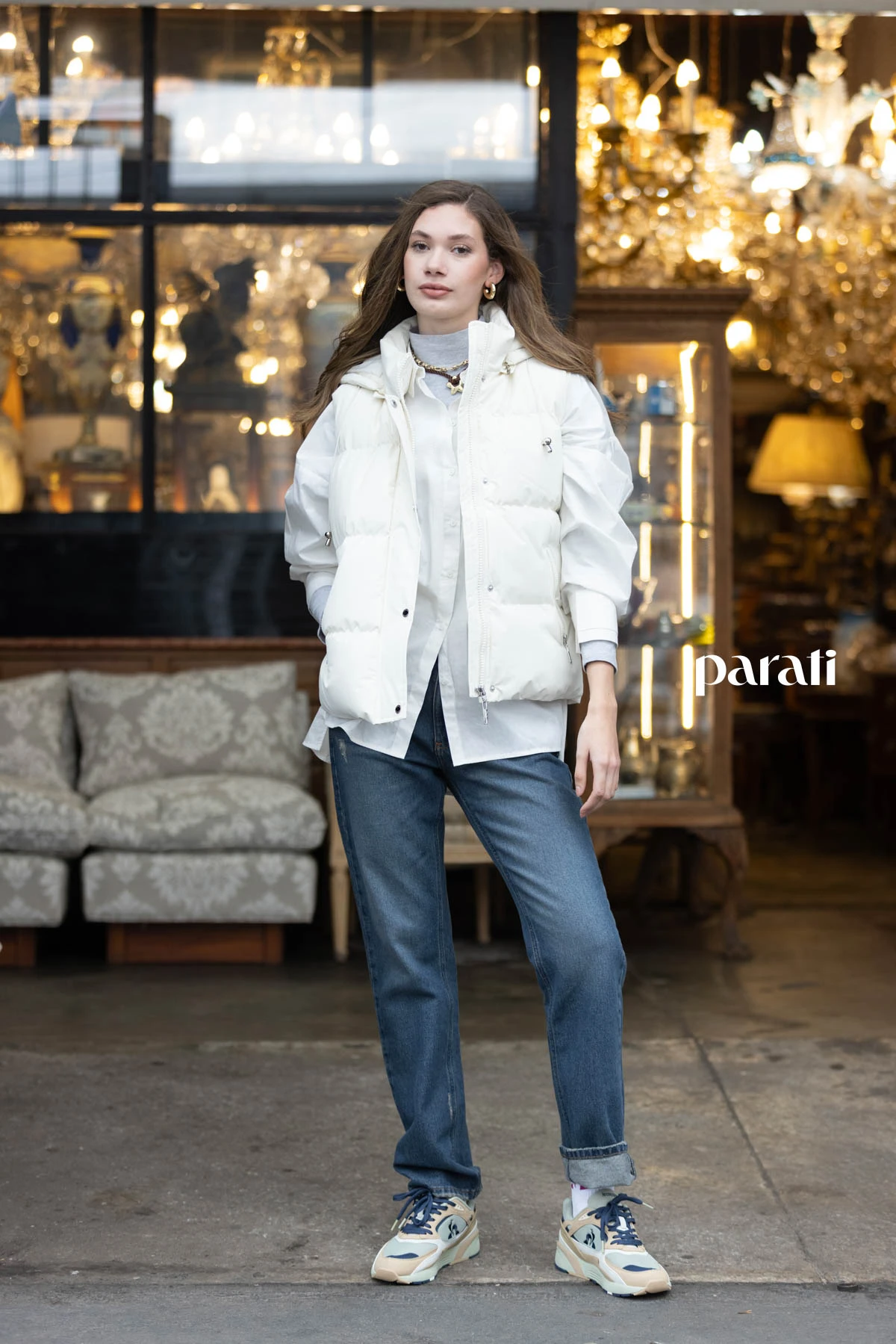 Chaleco puffer blanco @perramusoficial, camisa blanca oversize @mishkabuenosaires, polera de algodón gris @boliviauniverso, jean recto azul @hausofdnm, collares cadena y cordón con dije, y aros argolla dorada @ritace.accesorios, zapatillas combinadas y medias @lecoqsportif_ar.