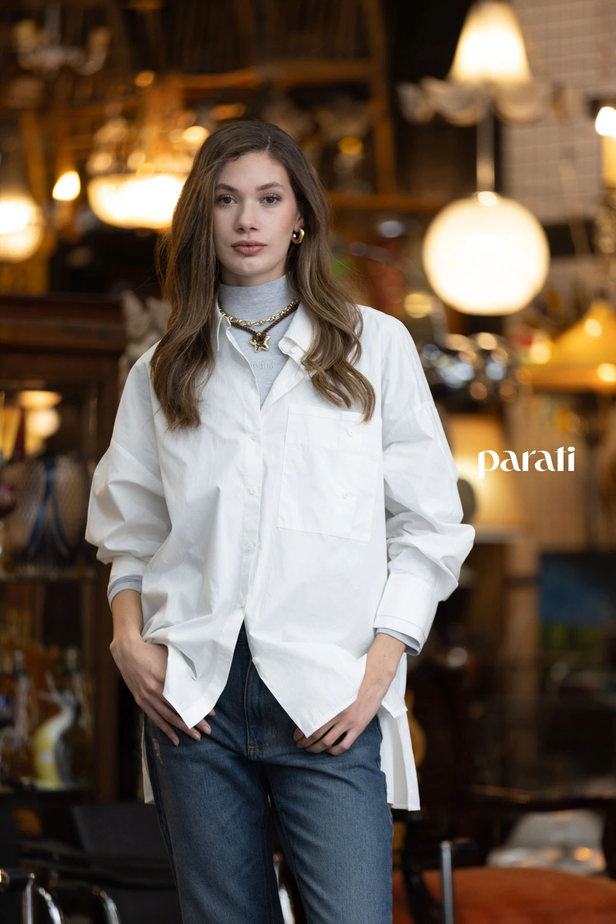 Chaleco puffer blanco @perramusoficial, camisa blanca oversize @mishkabuenosaires, polera de algodón gris @boliviauniverso, jean recto azul @hausofdnm, collares cadena y cordón con dije, y aros argolla dorada @ritace.accesorios, zapatillas combinadas y medias @lecoqsportif_ar.