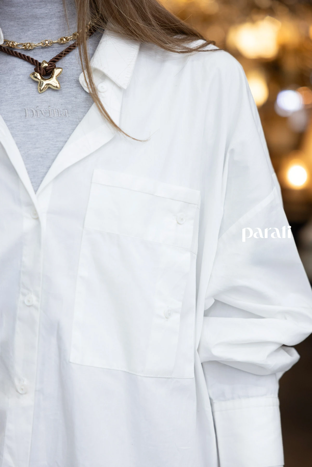 Chaleco puffer blanco @perramusoficial, camisa blanca oversize @mishkabuenosaires, polera de algodón gris @boliviauniverso, jean recto azul @hausofdnm, collares cadena y cordón con dije, y aros argolla dorada @ritace.accesorios, zapatillas combinadas y medias @lecoqsportif_ar.