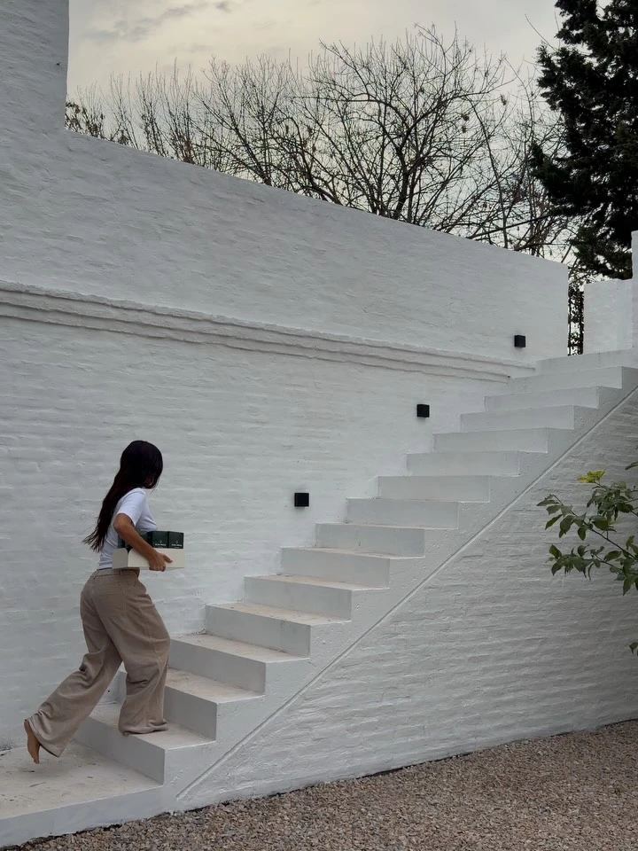 El jardín mantiene la misma estética minimalista del interior, con paredes blancas, escaleras que conectan distintos niveles y amplios espacios abiertos que potencian la luz natural y la sensación de amplitud.