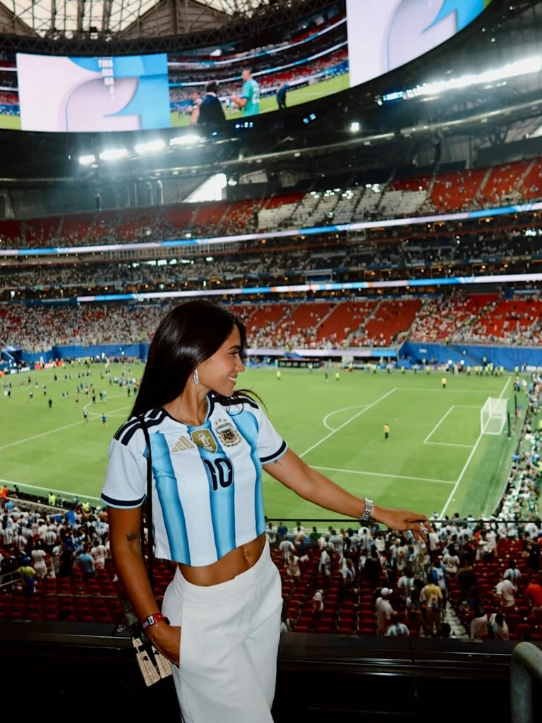 Llevó la camiseta oficial de la Selección Argentina intervenida en versión cropped, combinada con un pantalón sastrero blanco de tiro medio que aportó un aire elegante al conjunto.