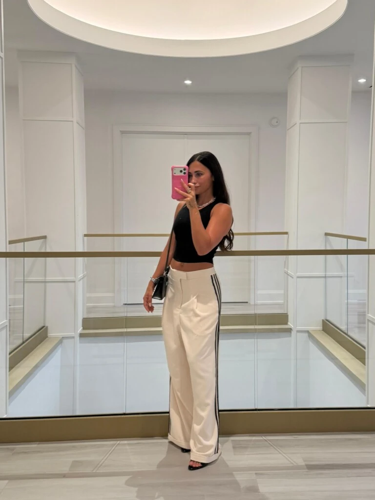 Para la ocasión, eligió un pantalón de vestir beige con rayas negras en los laterales, un top negro y una cartera del mismo tono.
