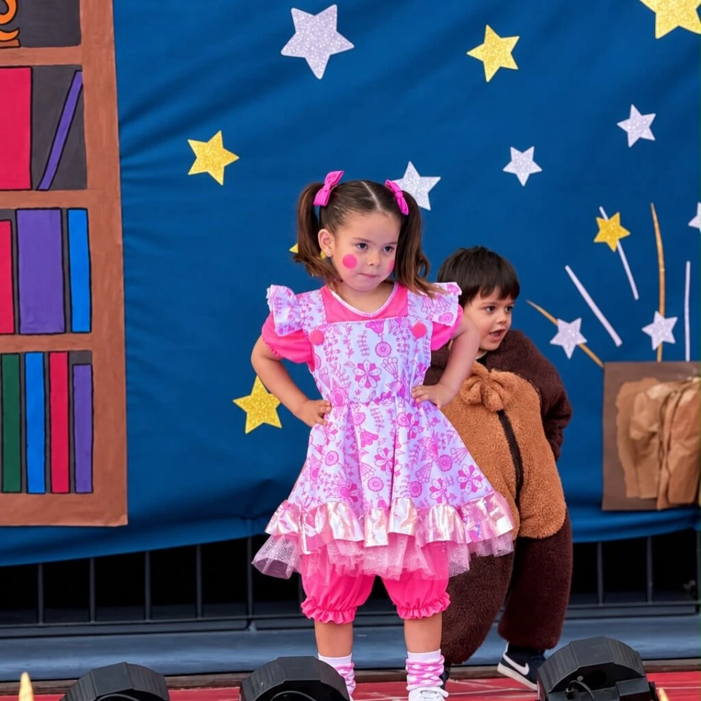 La pequeña llevó medias altas de algodón con rayas y detalles en blanco y rosa pastel, combinadas con zapatillas urbanas blancas que aportaron comodidad para disfrutar de la presentación.